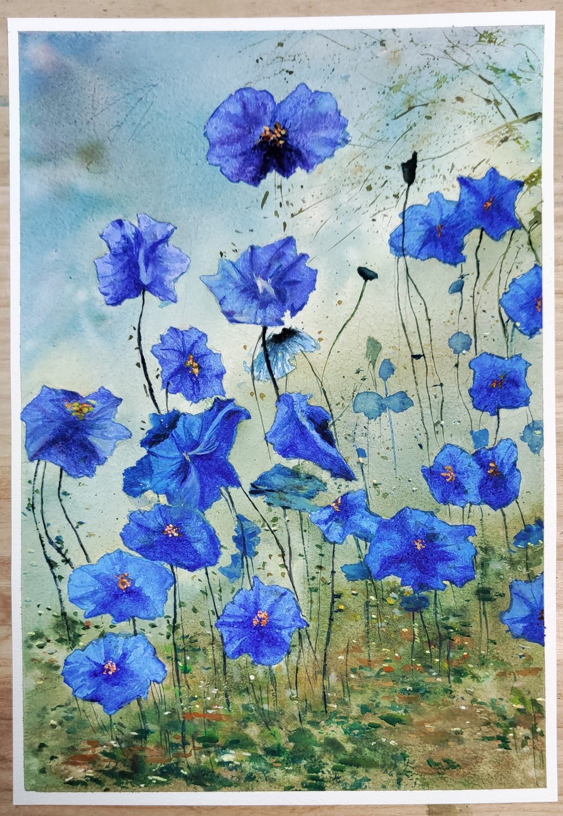 Watercolor of bright blue flowers scattered across a pale meadow