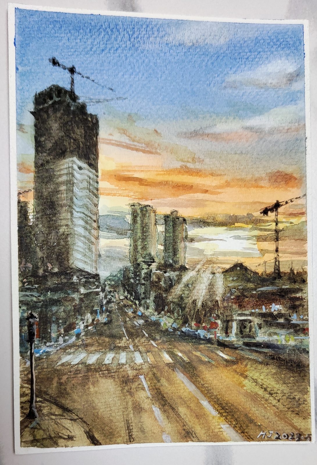 Watercolor of a city street at sunset with a tower crane above a high-rise under construction