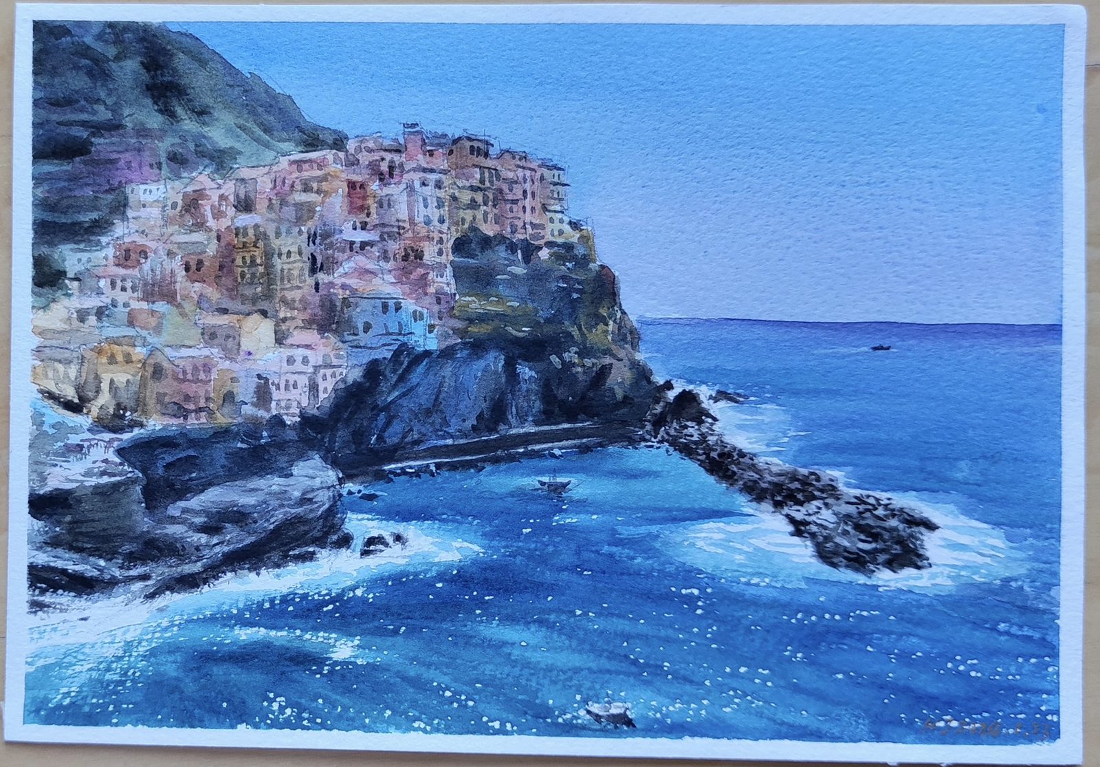 Watercolor of the colorful cliffside village of Manarola above a bright blue sea