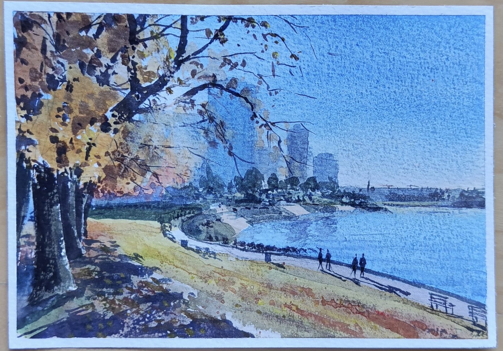 Watercolor of a waterside path under autumn trees with the city skyline beyond