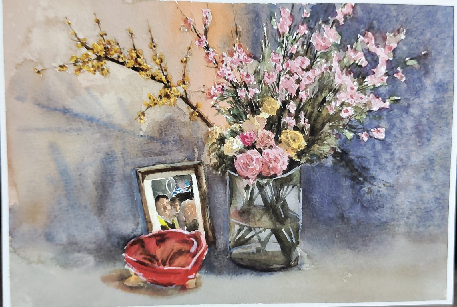 Watercolor still life of spring blossoms in a vase beside a small framed photo